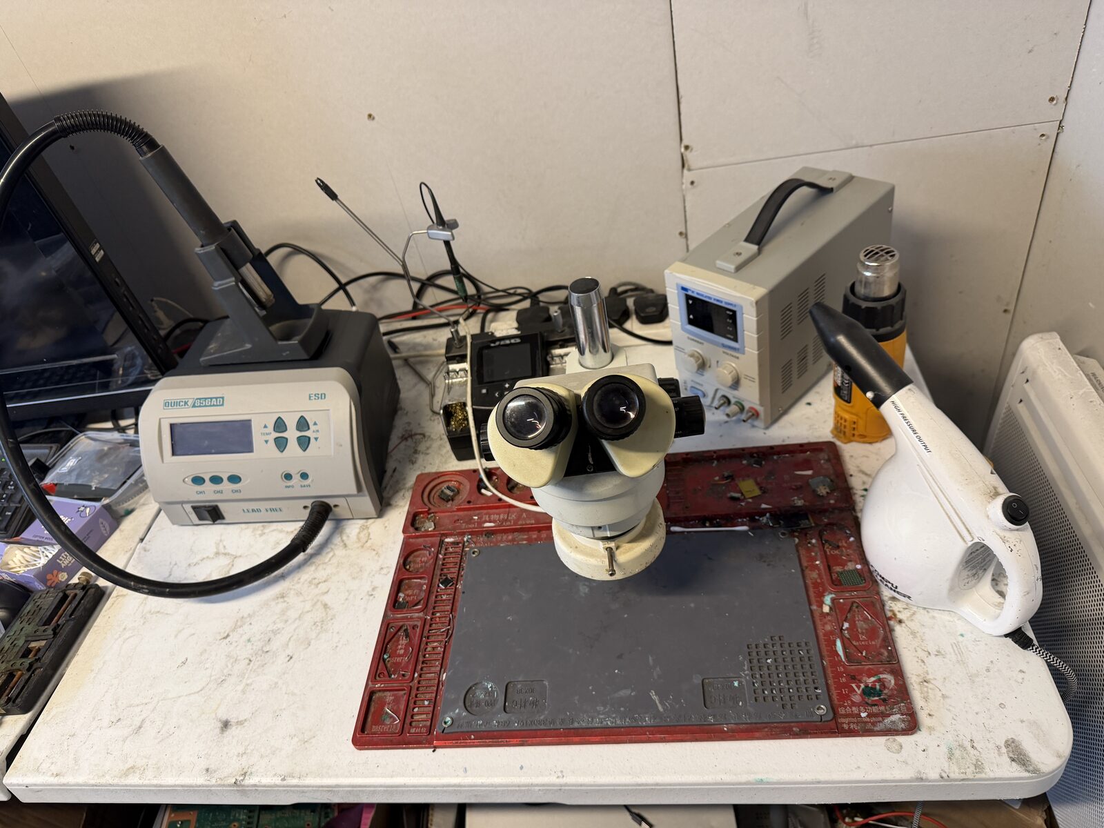 Overhead or angled shot of the workbench with soldering iron, hot-air station, and microscope in frame