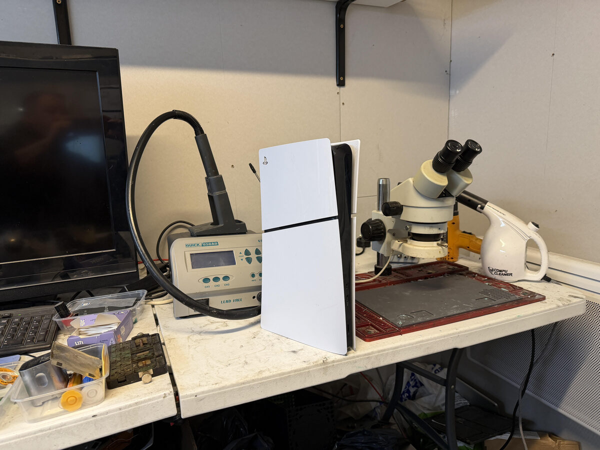 Wide shot of the workbench with soldering station, microscope, and tools visible