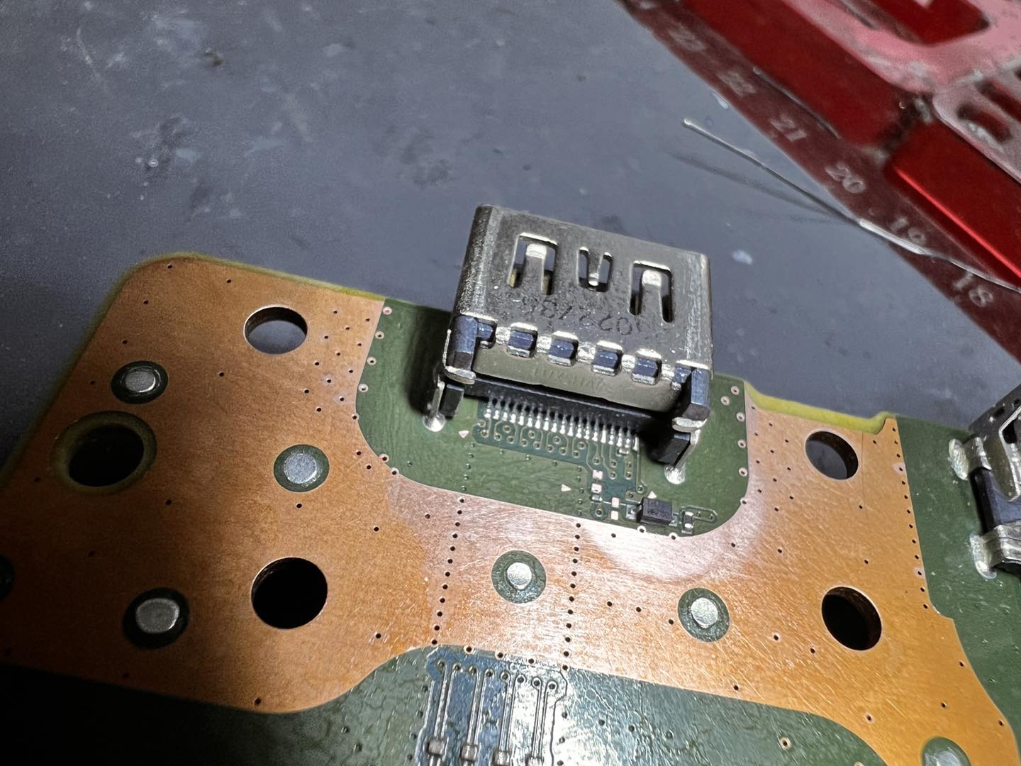 Close-up microscope view of HDMI port being soldered at the workbench